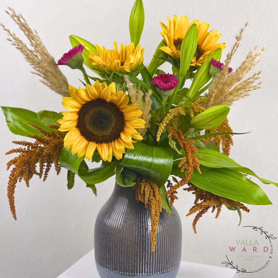Bouquet of sunflowers and other flowers in a gray vase on a white background