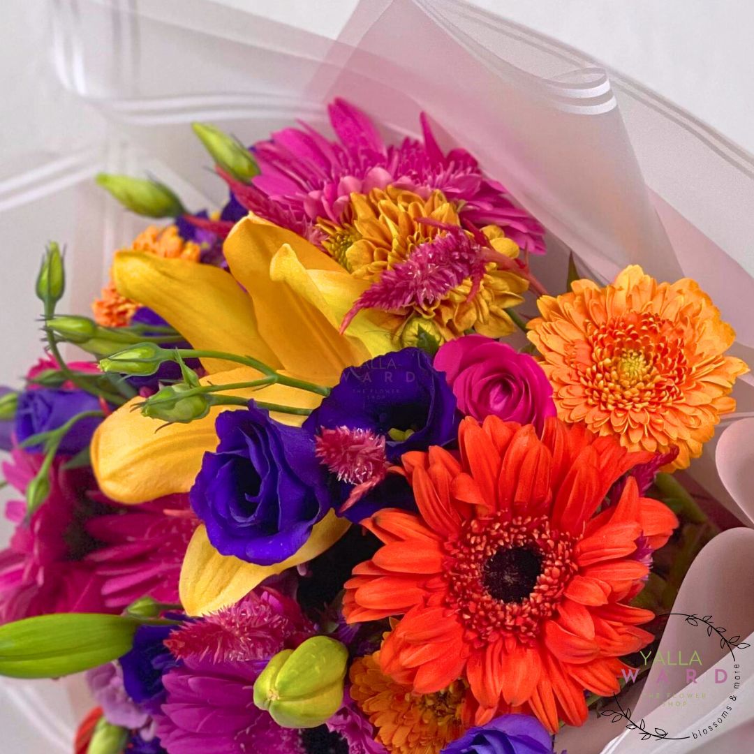 Bouquet of colorful flowers including orange, purple, yellow, and pink in a pink warp.