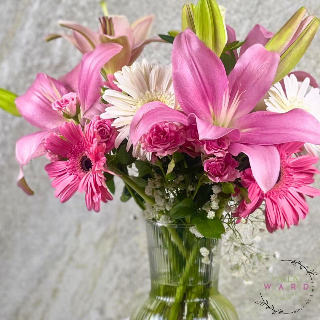 pink and white flowers in a clear vase on a textured gray background