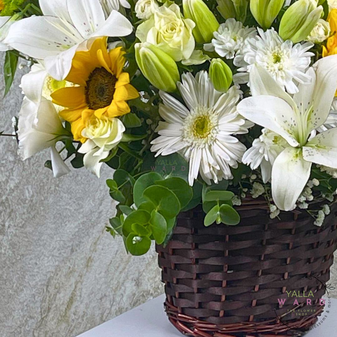 Basket of flowers with white, yellow, and green flowers on a light background