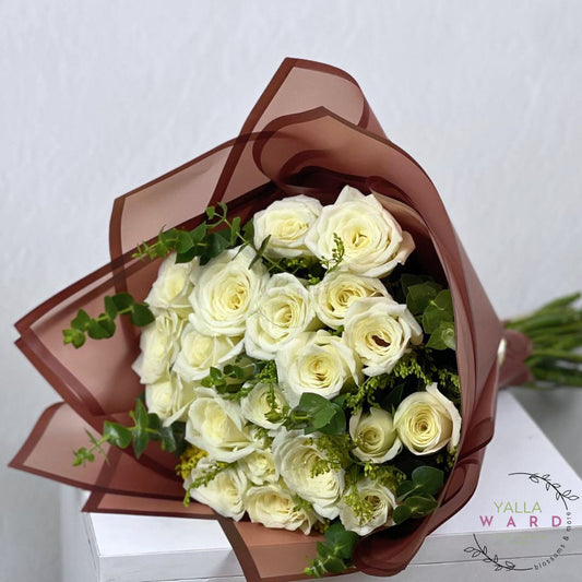 Bouquet of white roses wrapped in brown paper on a light background