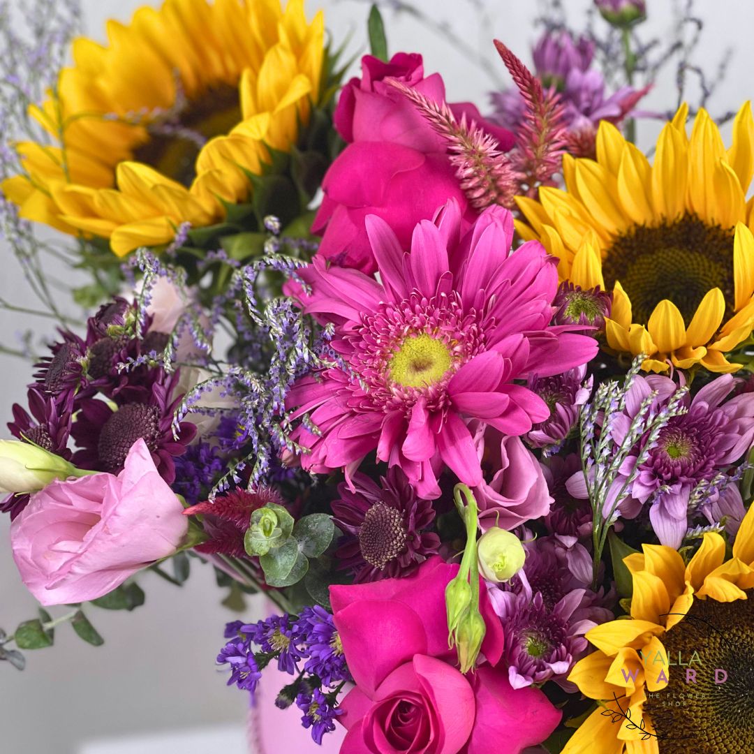 box of colorful flowers including sunflowers, roses, and daisies.