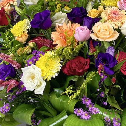 Bouquet of colorful flowers including roses and daisies with a brand name visible.