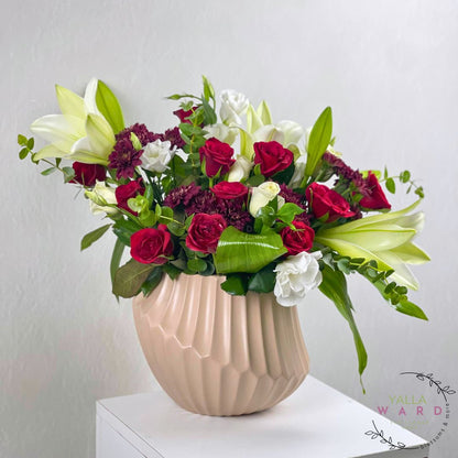 Floral arrangement in a beige vase on a white surface with a light gray background