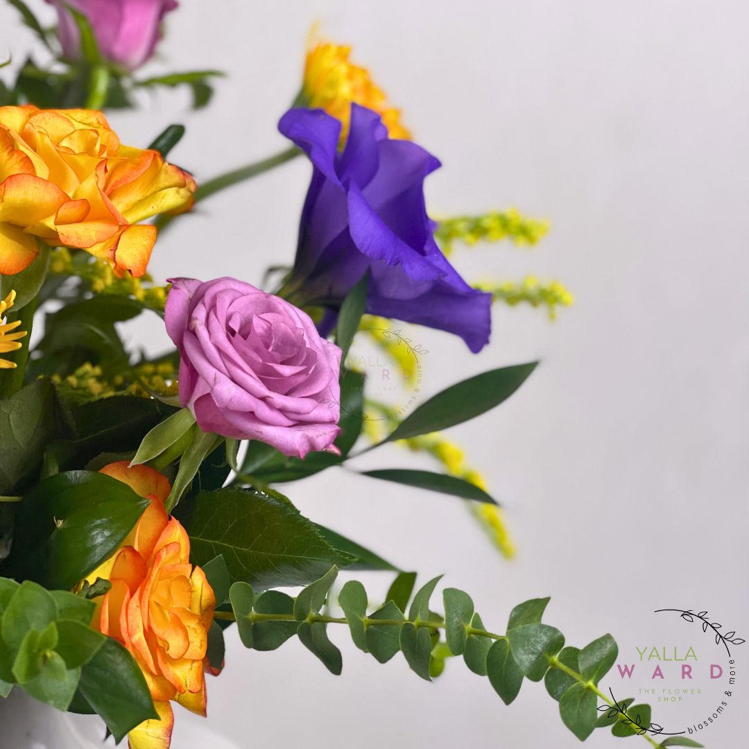 Bouquet of colorful flowers including purple, orange, and yellow on a white background with 'Yalla Ward' branding.