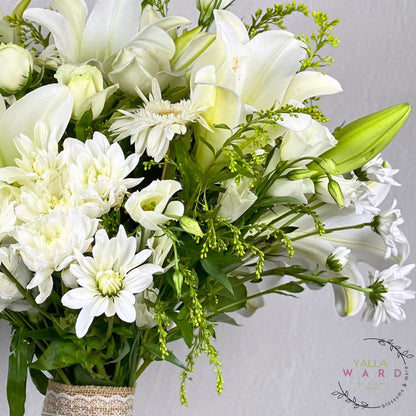 Bouquet of white flowers with greenery on a gray background, featuring the Yalla Ward logo.