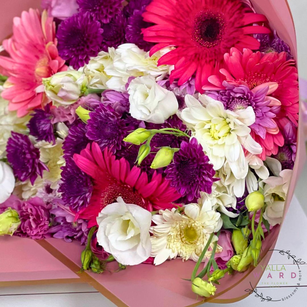 pink and white bouquet of flowers including pink, purple, and white flowers on a pink background.