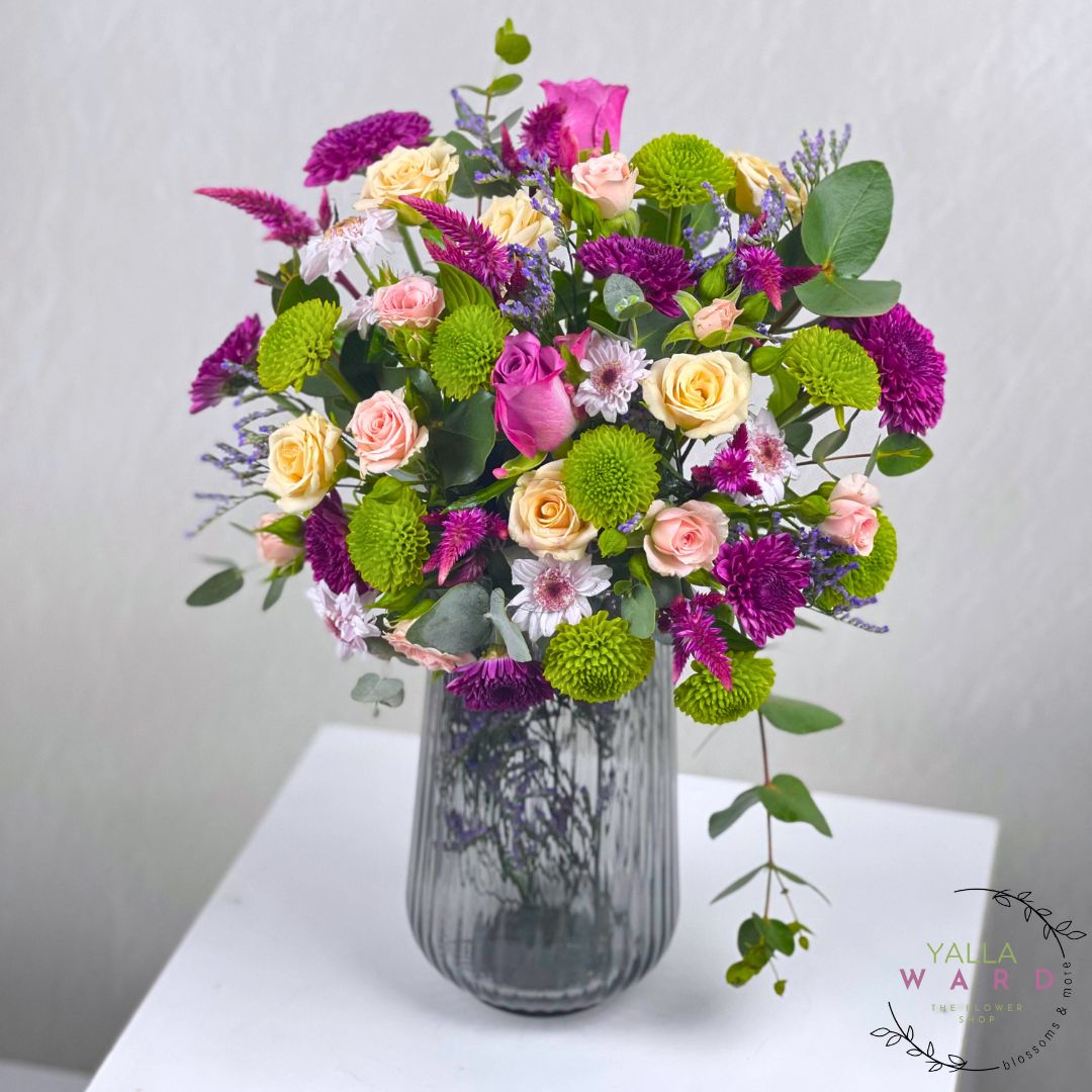 colorful flowers in a gray vase on a white surface with a light gray background.