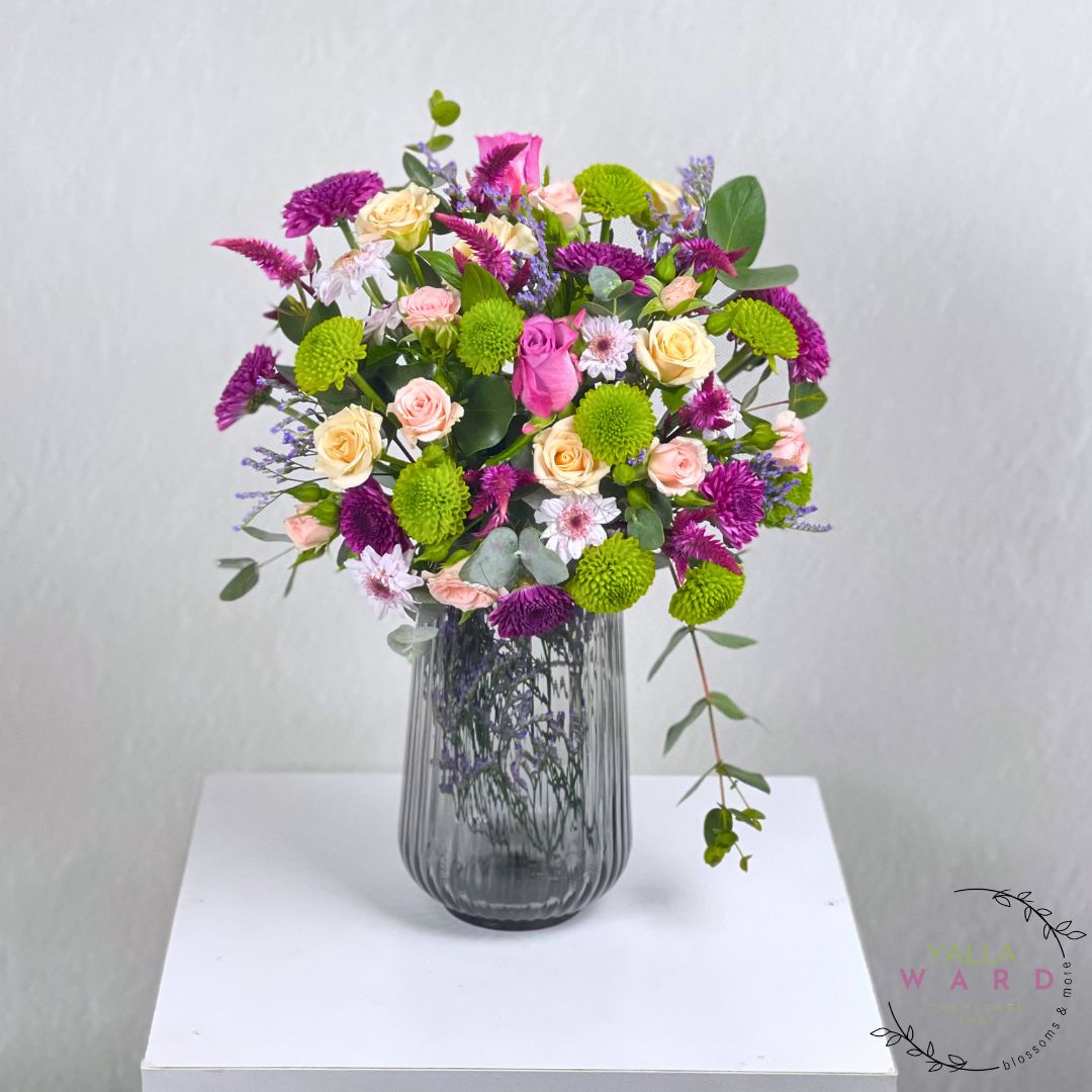 colorful flowers in a gray vase on a white surface with a light gray background.