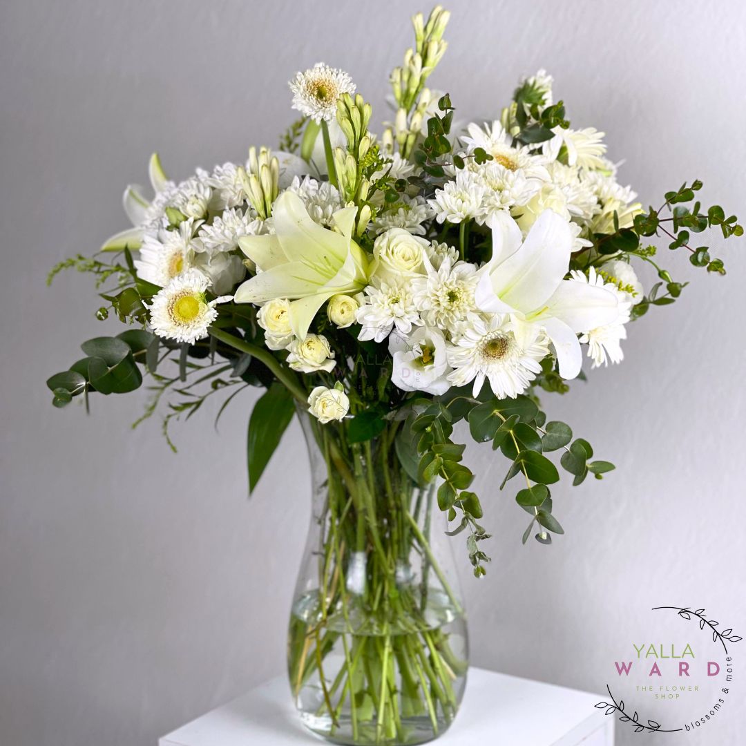 white and green flowers in a clear vase on a gray background with 'Yalla Ward' branding.
