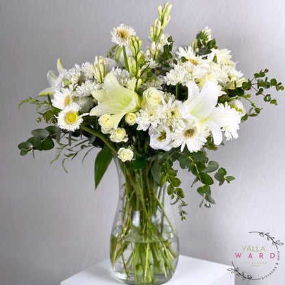 white and green flowers in a clear vase on a gray background with 'Yalla Ward' branding.