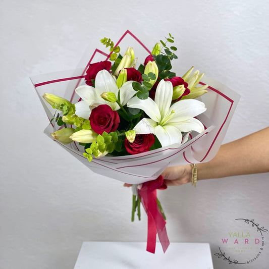 Bouquet of red roses and white lilies held by a hand against a light gray background, with 'Yalla Ward' branding.