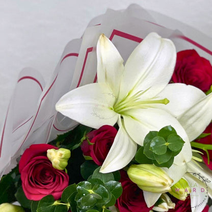 Bouquet of red roses and white lilies with a white ribbon on a light gray background