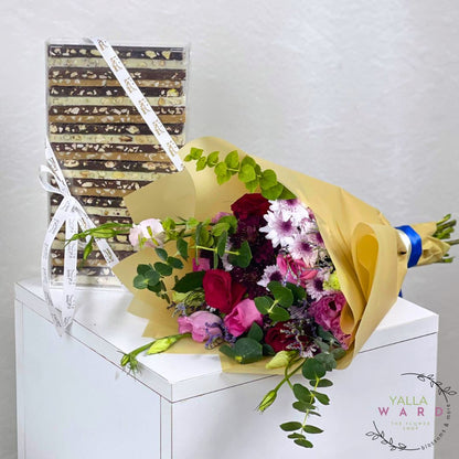 Bouquet of flowers wrapped in yellow paper with Chocolate Sticks, featuring the brand 'Yalla Ward'.