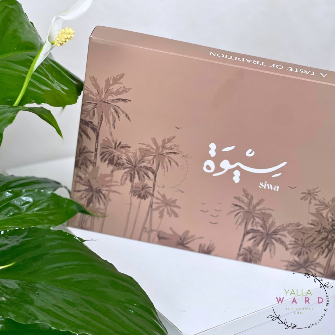 dates box with palm tree design and text on a white surface with green leaves.