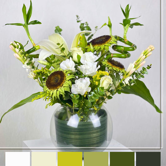 flowers in a green vase on a white surface with a light gray background