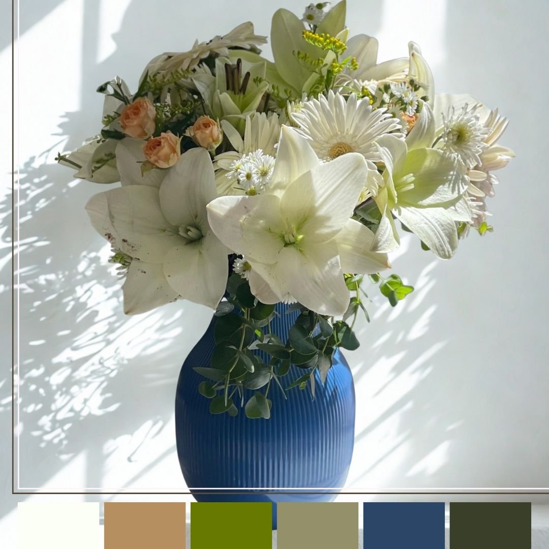 Bouquet of flowers in a blue vase against a white wall with color swatches below.
