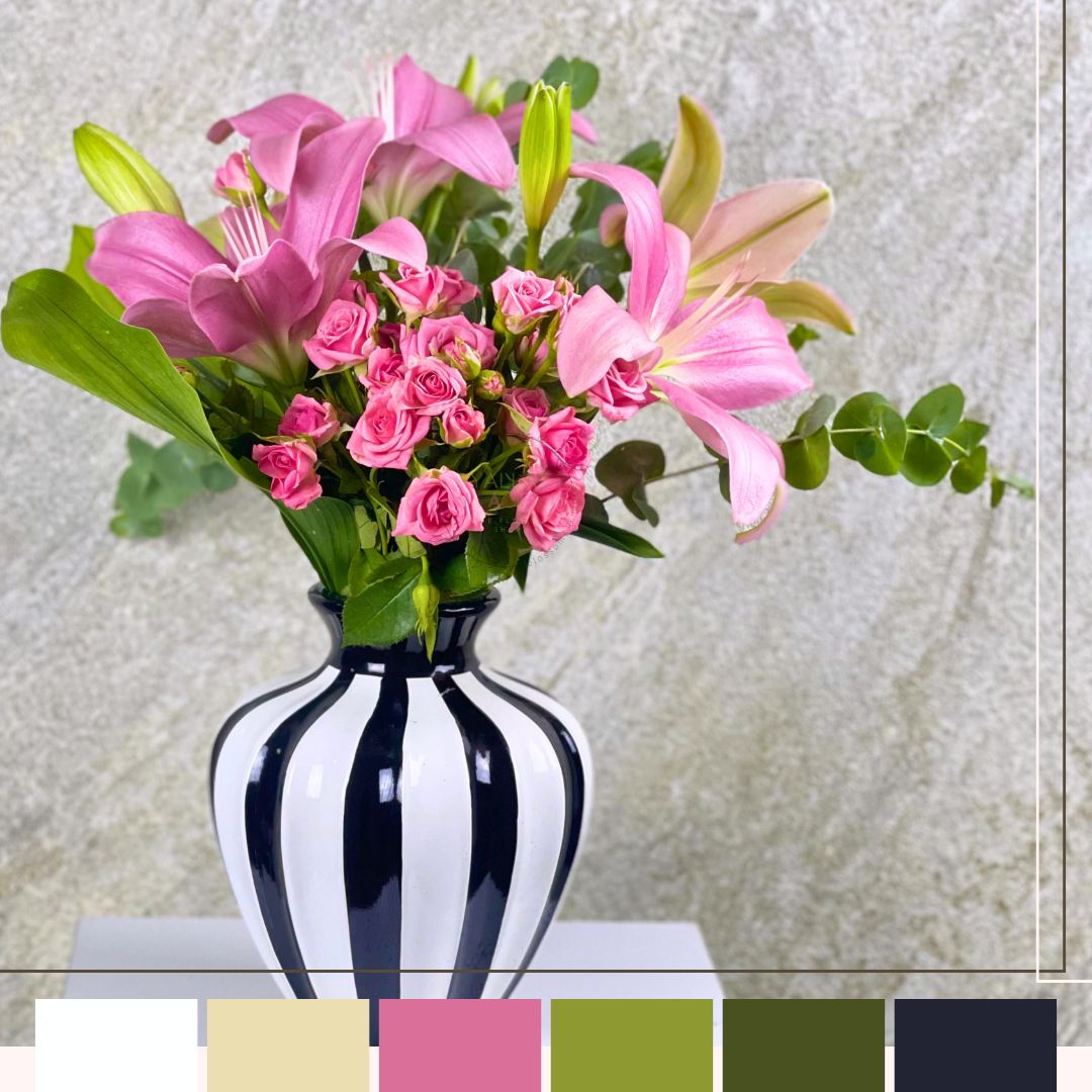 Bouquet of pink flowers in a black and white striped vase on a light gray background