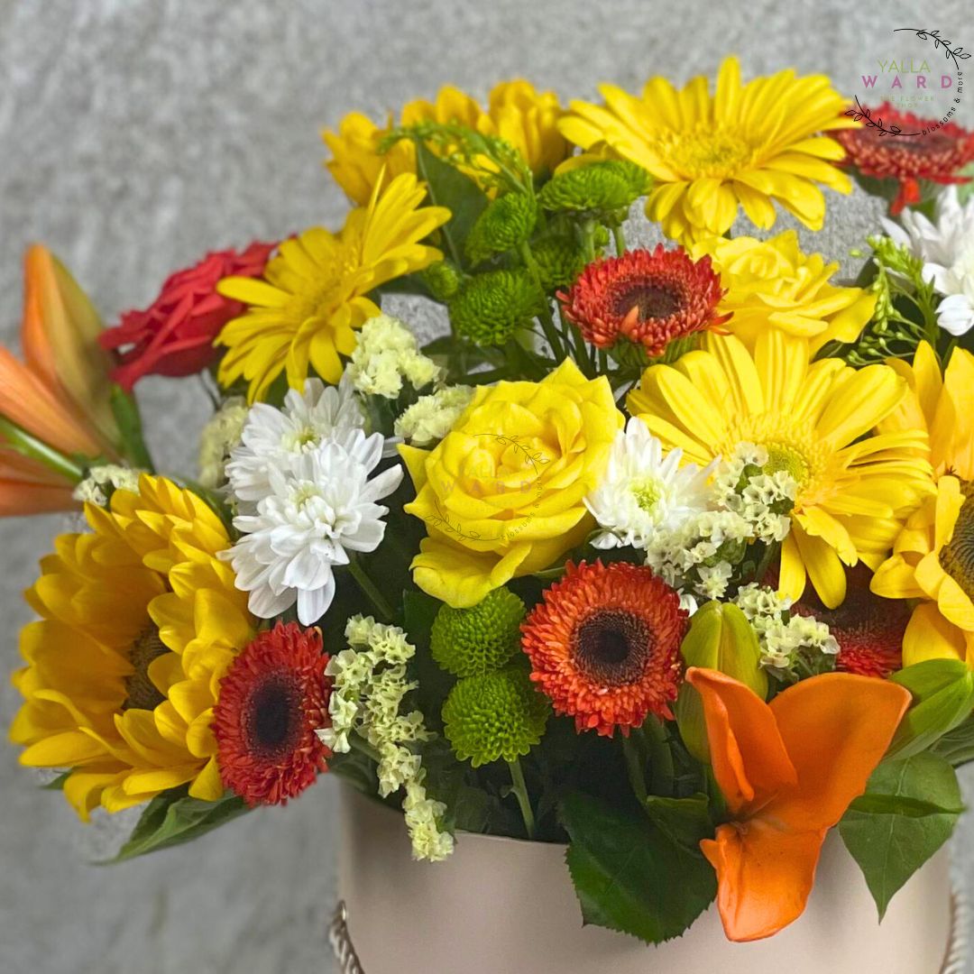 Bouquet of colorful flowers including yellow, red, and white in a white box.