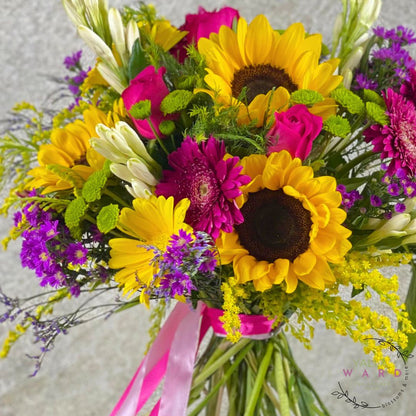 Bouquet of sunflowers, pink and white flowers with a pink ribbon on a light background.
