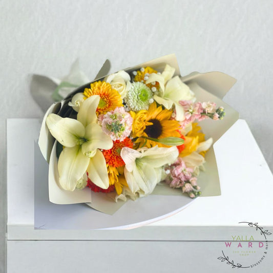 Bouquet of flowers wrapped in paper with a visible brand logo on a white surface.