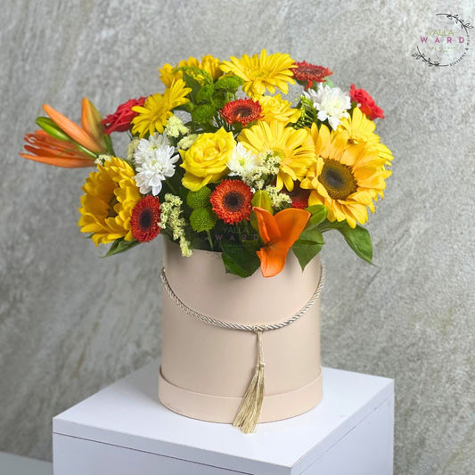 Colorful flower  in a beige box with a tassel against a gray background