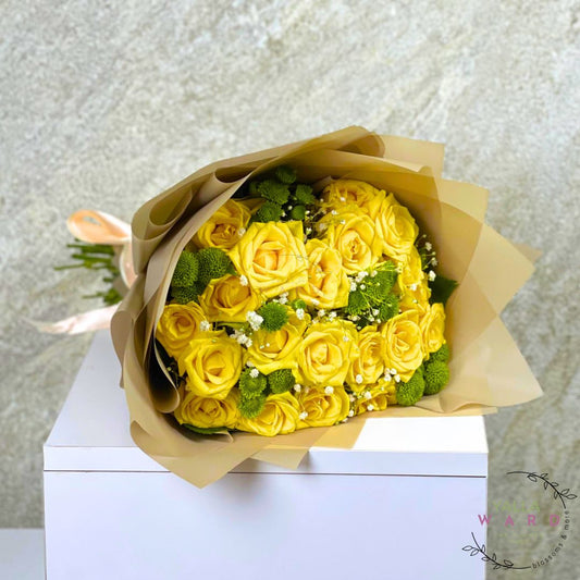 Bouquet of yellow roses wrapped in brown paper on a white surface with a light gray textured background.