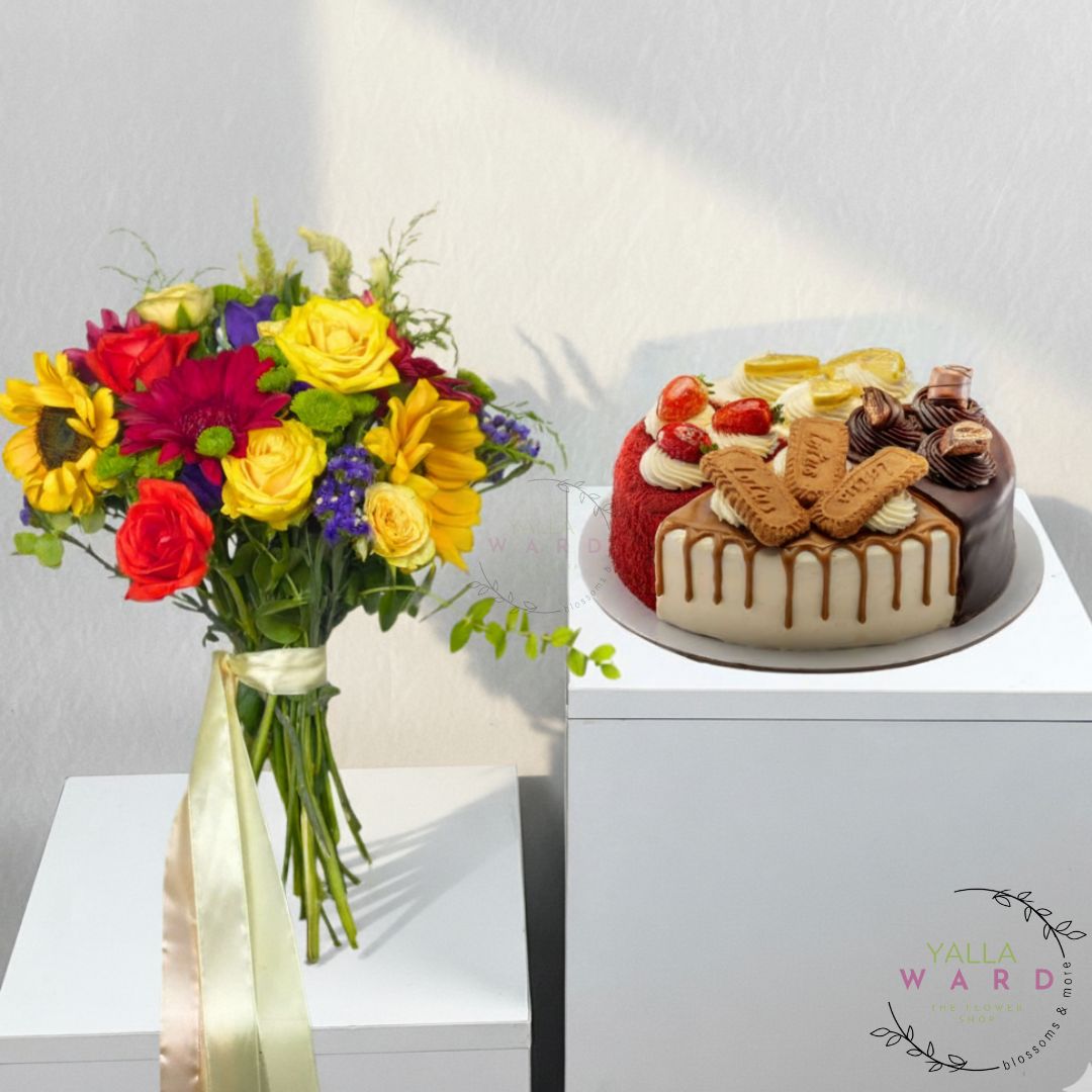 Colorful bouquet of flowers and a decorative cake on a white surface with a visible brand logo.