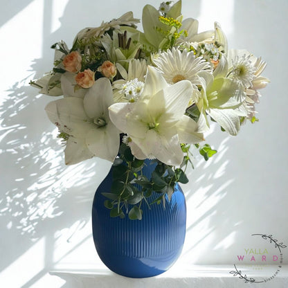 Blue vase with a bouquet of white and green flowers on a white background